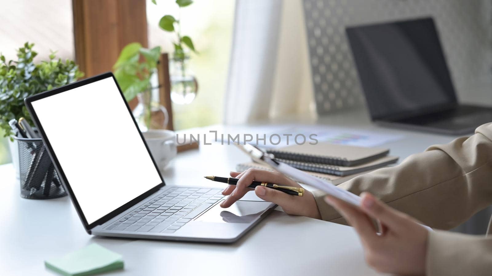 Cropped shot young woman holding clipboard and typing on laptop computer.