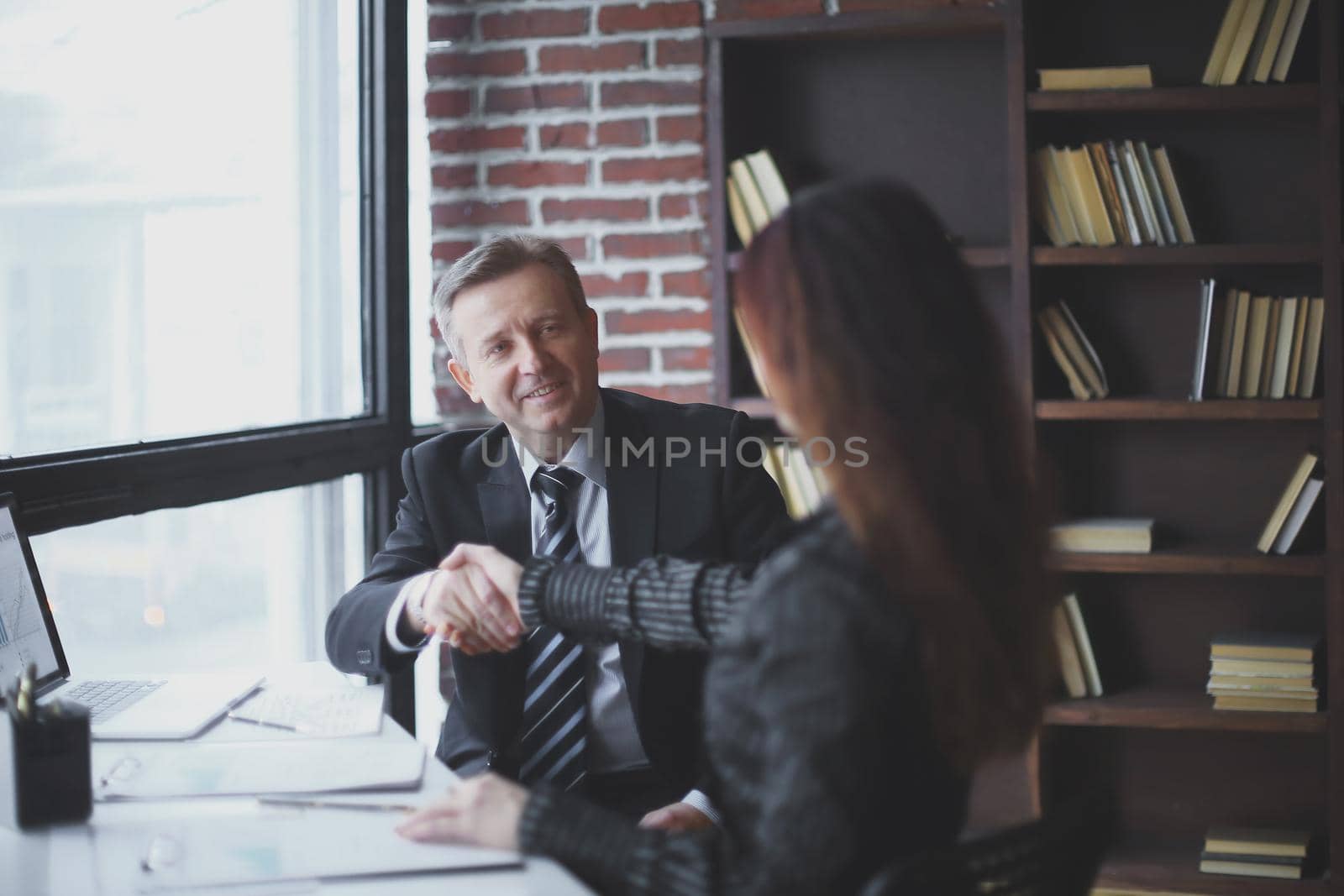 handshake of business partners sitting at their Desk in the office.