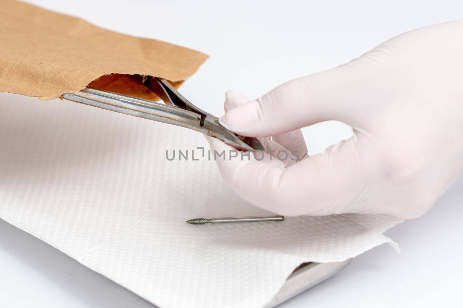 Close-up of manicurist hand is taking manicure tool from craft envelope in manicure salon.