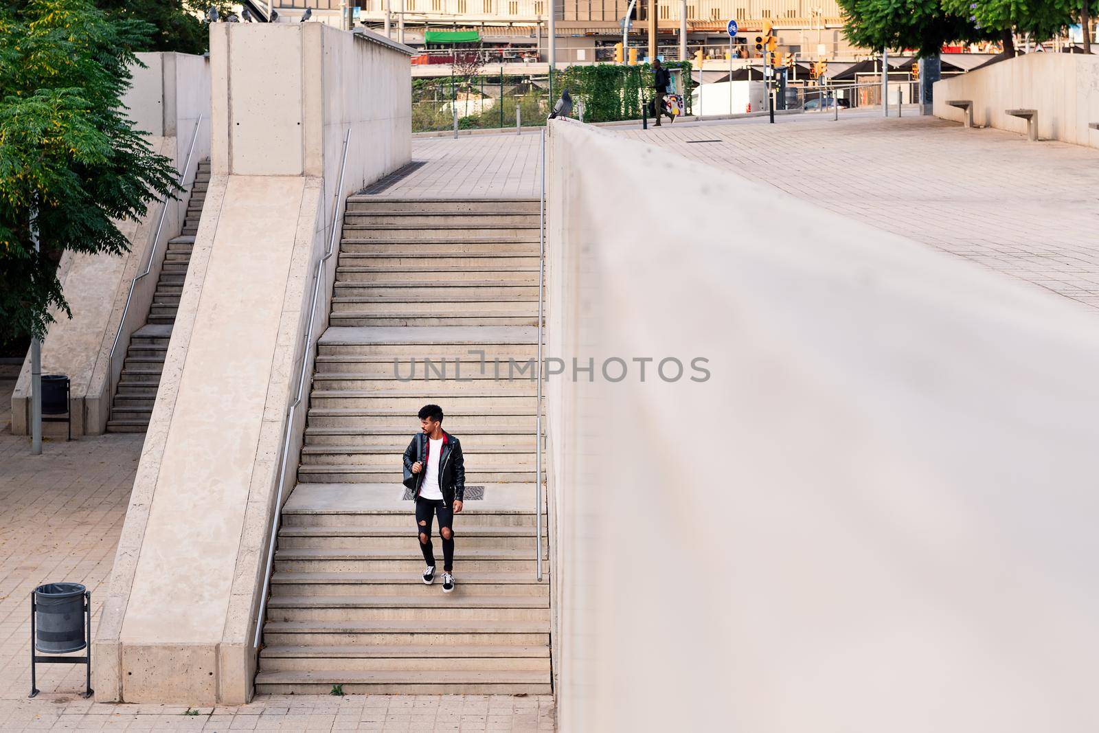 young latin man with backpack walking down city stairs, concept of urban lifestyle