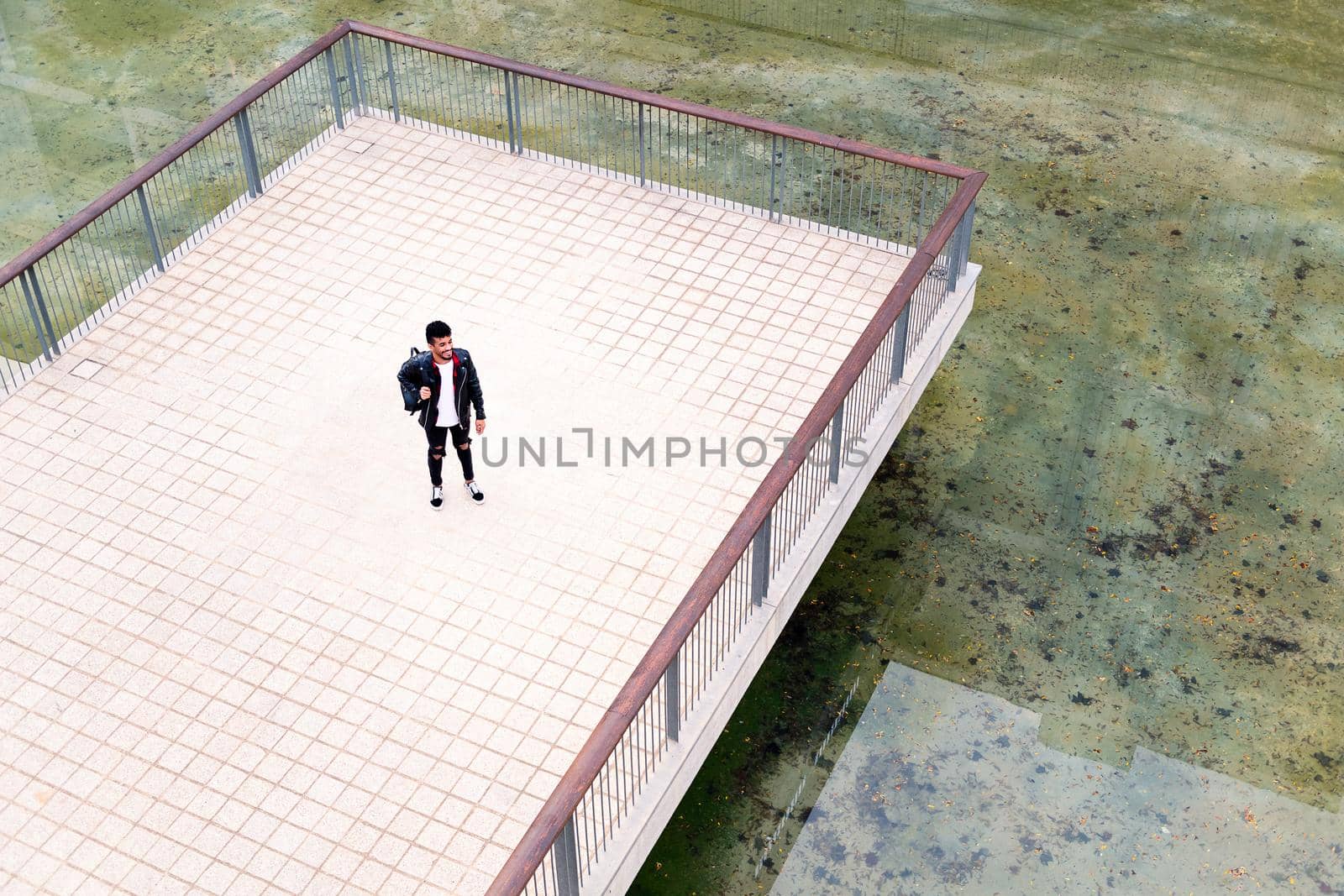 young urban student standing on a platform next to the lake in a city park, concept of urban lifestyle