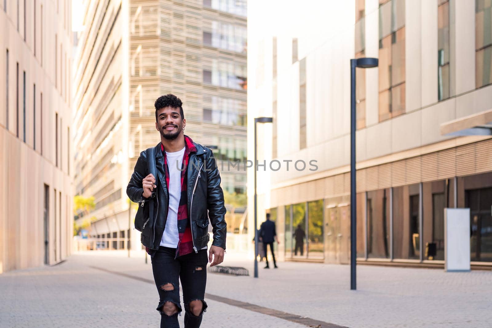 stylish young latin man walking happy in the city with his backpack, concept of urban lifestyle