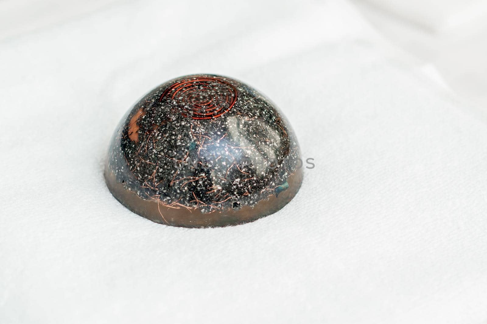 Close up of hot black massage stone sitting on white towel in spa.
