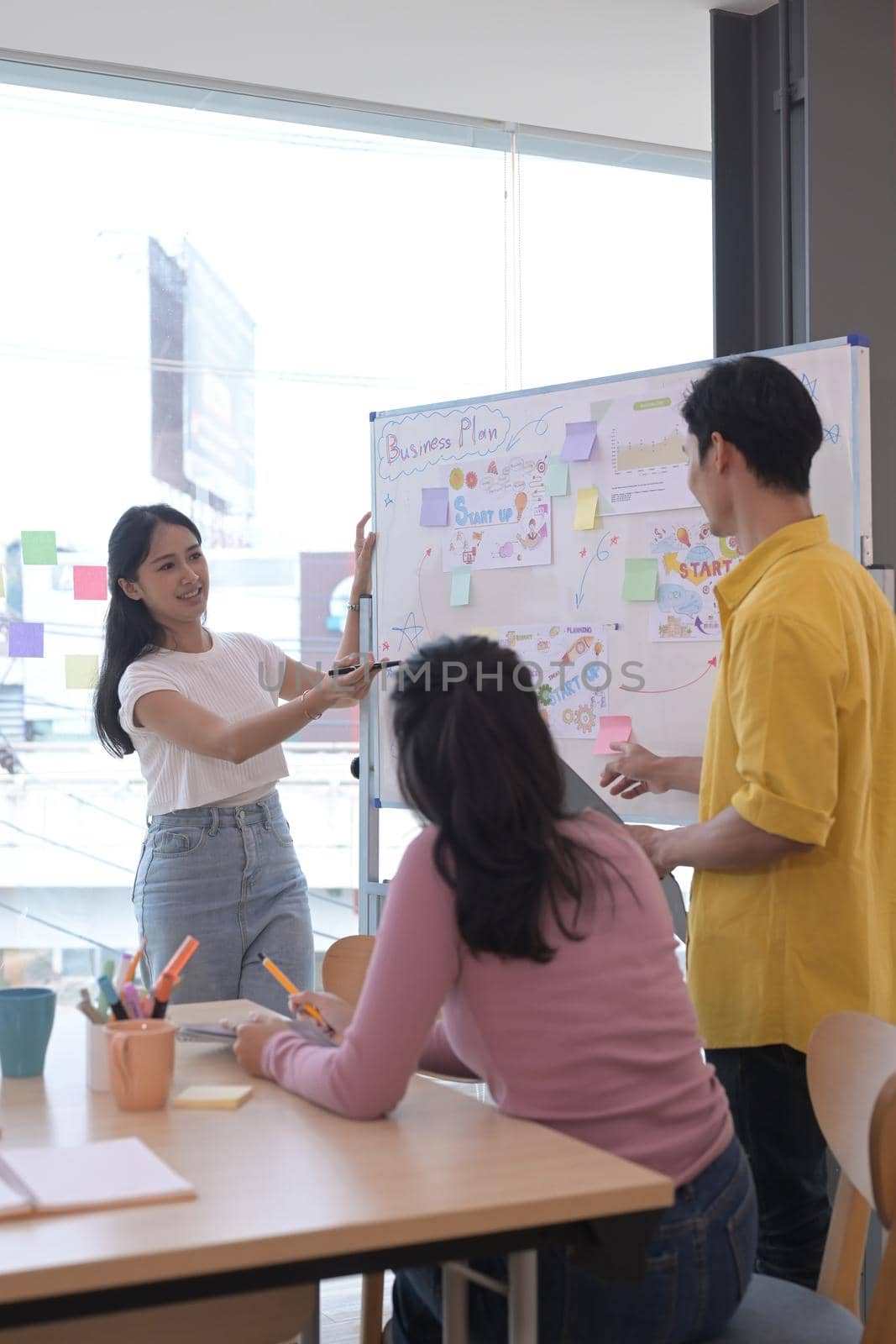 Beautiful asian woman giving presentation start up business strategy in meeting.