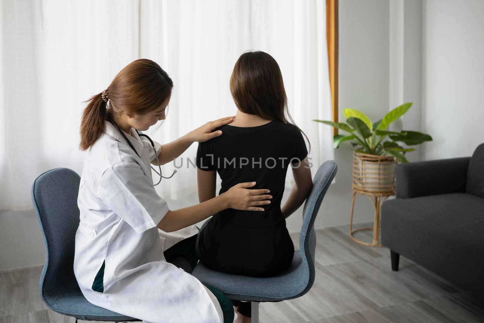 Physiotherapist examining treating injured back female patient in clinic.