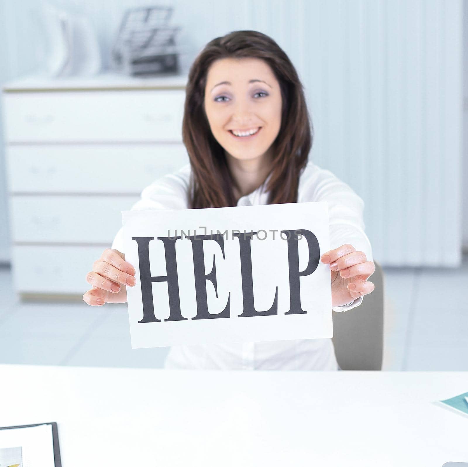 smiling business woman showing a sheet with the word help . photo with copy space
