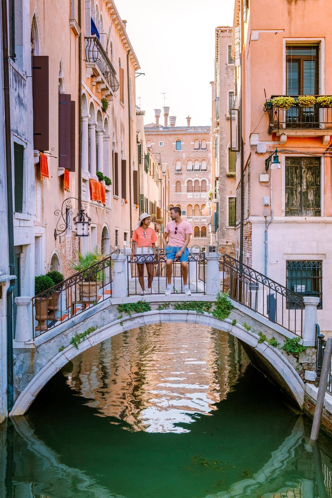 Venice Italy couple men and woman on a city trip at Venice, men and woman at waterfront looking at the famous Rialto bridge in Venice Italy by fokkebok