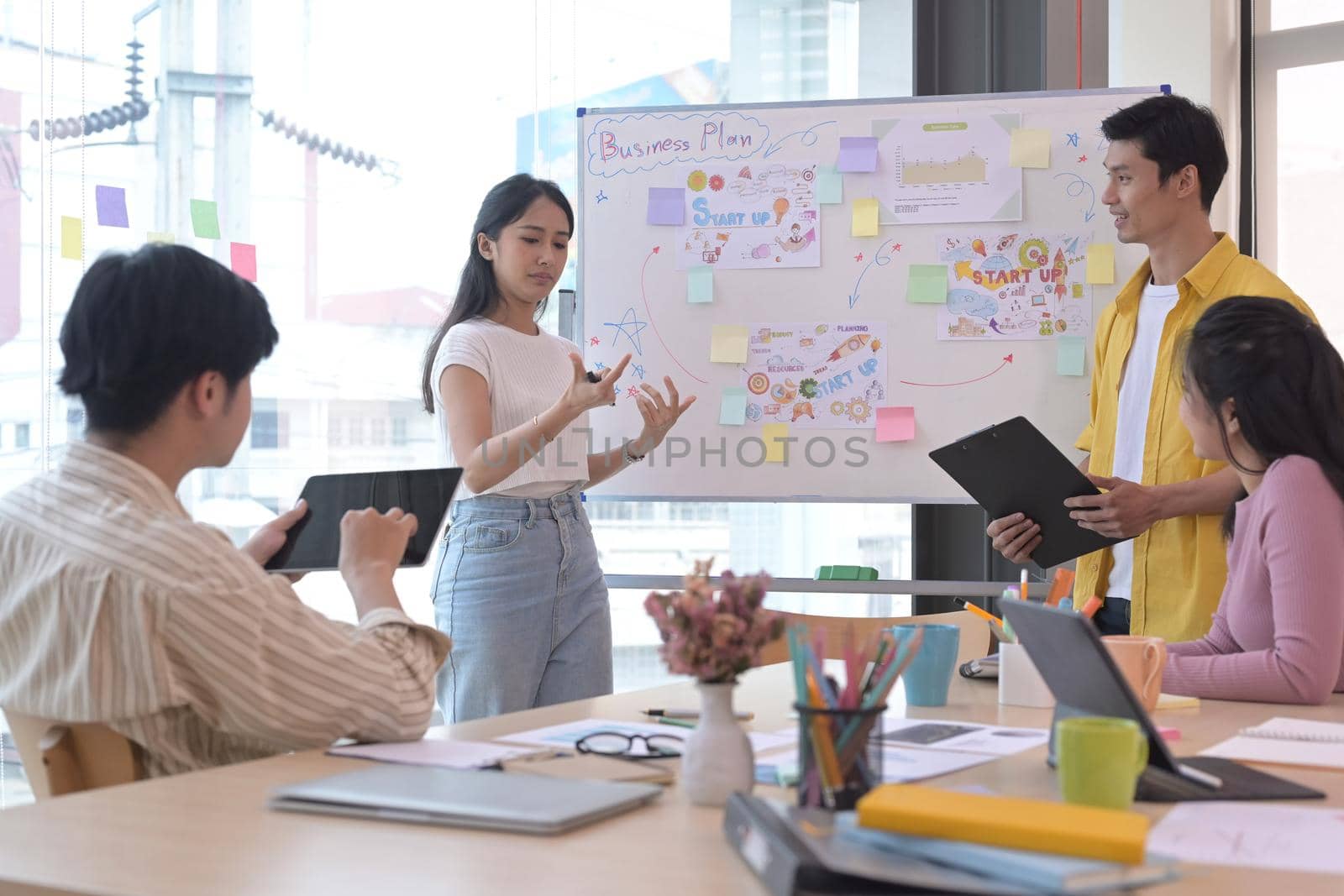 Business team leader giving presentation start up business strategy for diverse employees in meeting. by prathanchorruangsak