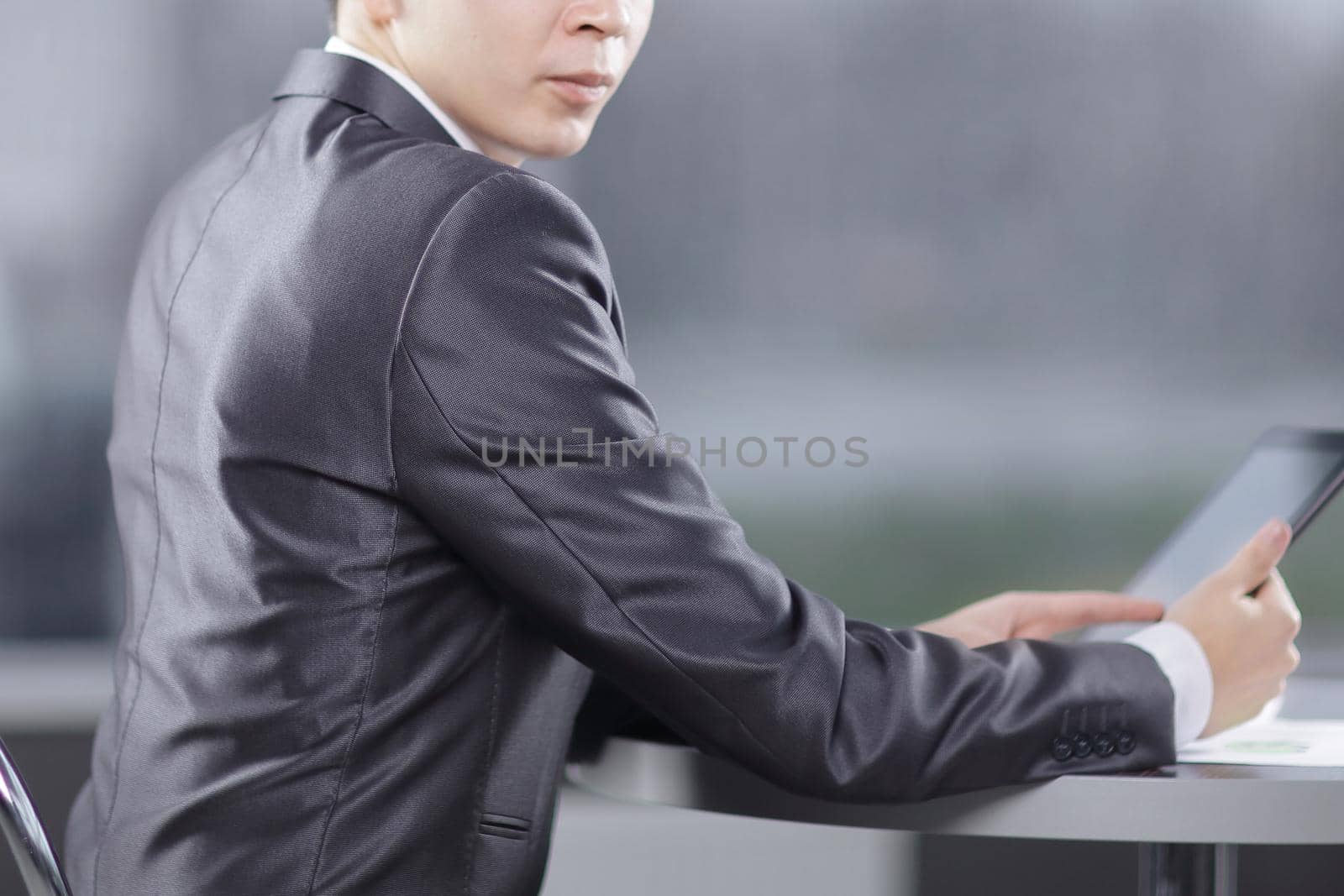 businessman with digital tablet sitting in a cafe near a large window.