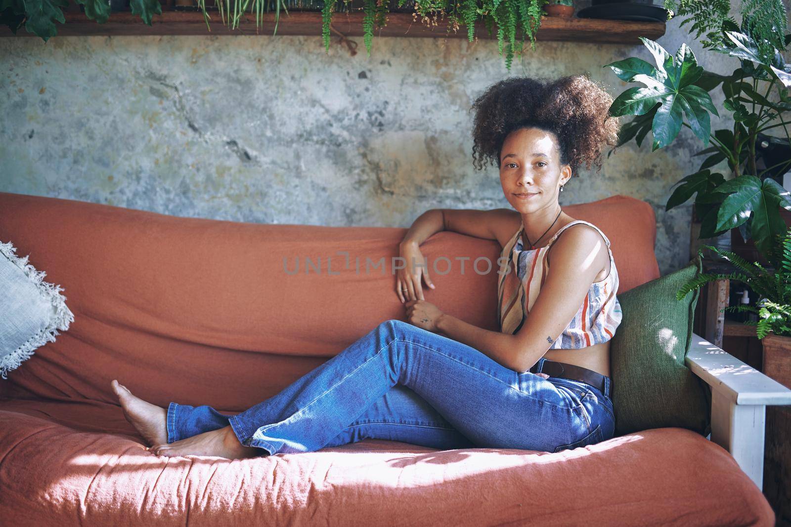 Shot of a beautiful African young woman relaxing on her sofa at home - Stock Photo