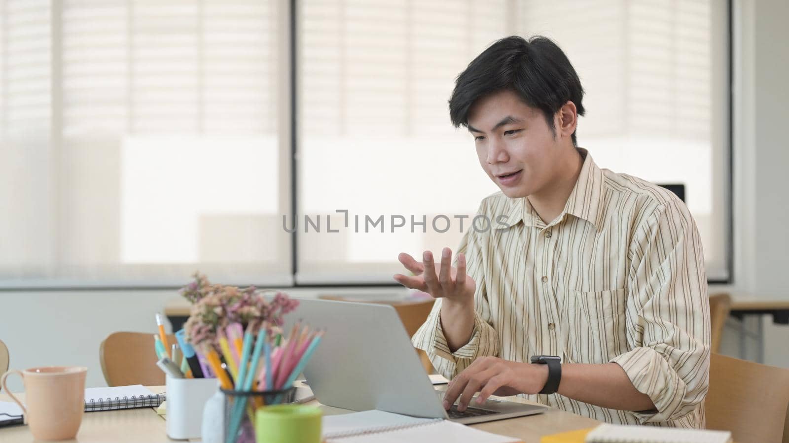 Handsome asian businessman having video conference with his business partner via laptop computer.