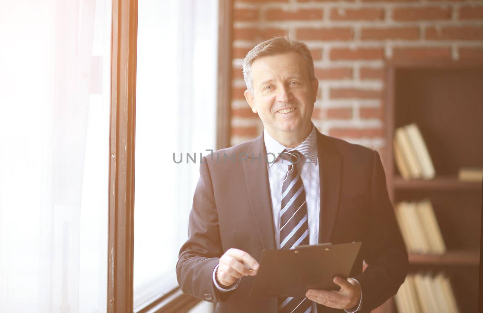 smiling senior businessman standing with document in office.business people