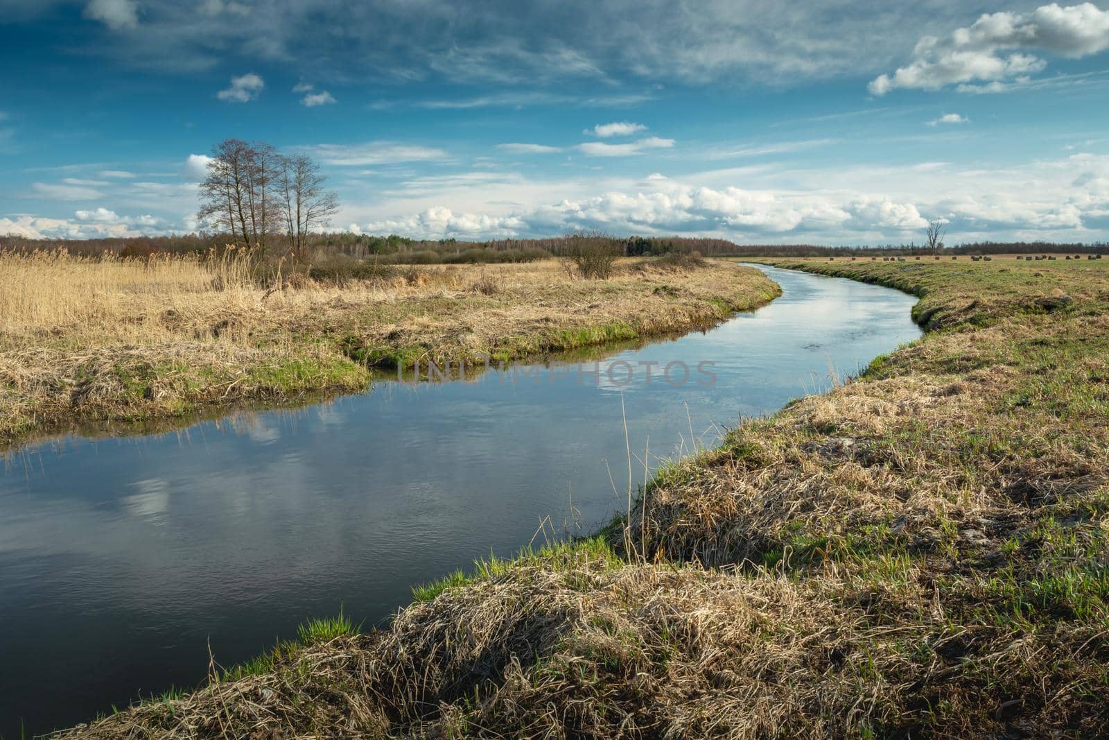 A bend in the calm river and clouds on the sky, spring view