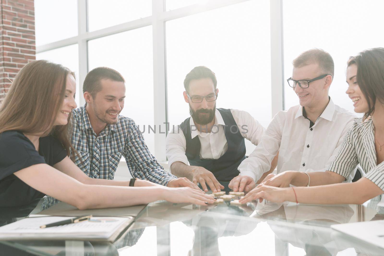 top view. business colleagues collecting puzzle, sitting at the table. business concept