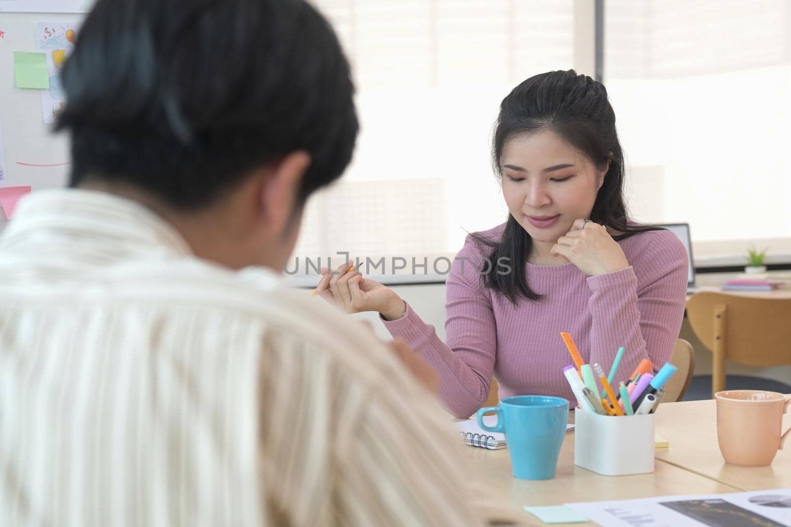 Pretty young woman discussing project plan with colleagues in meeting.