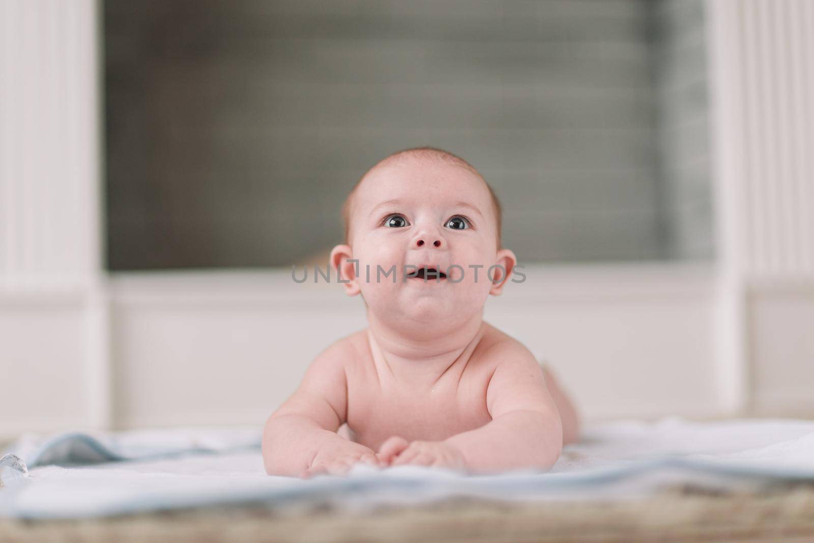 pretty baby lying down and looking up in surprise. photo with copy space