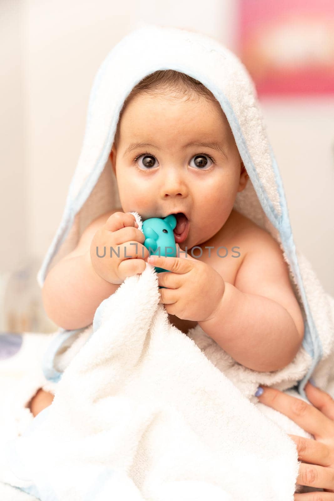 Baby boy wearing diaper and white towel in white sunny bedroom. Newborn child relaxing in bed after bath or shower. Nursery for children. New born kid with toy bear. High quality photo