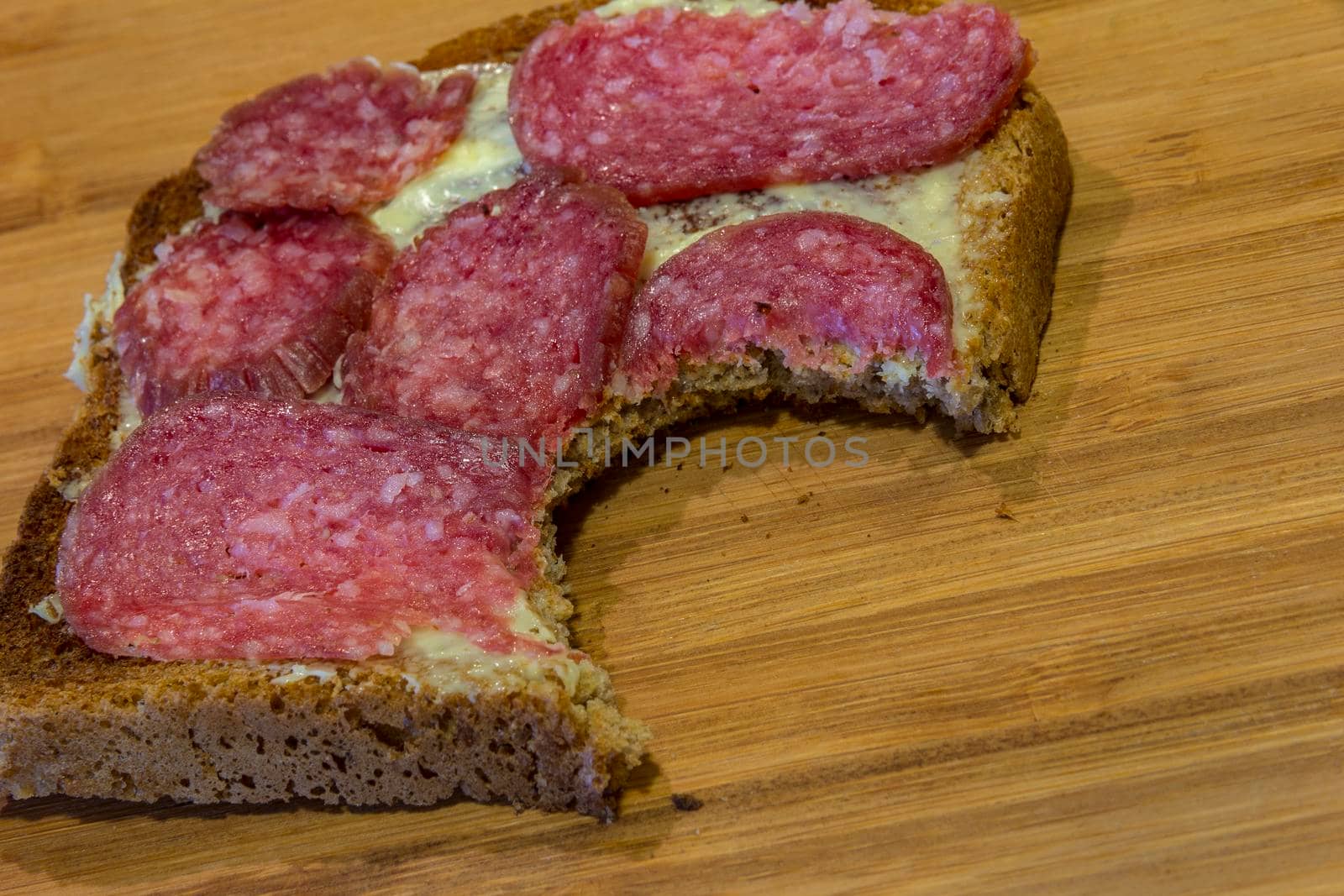 a bitten slice of salami. Lean breakfast. Bitten sandwich. Close up 