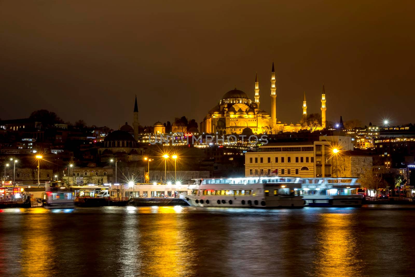 Illuminated Istanbul at night. Turkey. Night view of historical part of Sultanahmet area Famous mosques, pier with boats, cafes, bars and shops. Bosphorus river with boats.