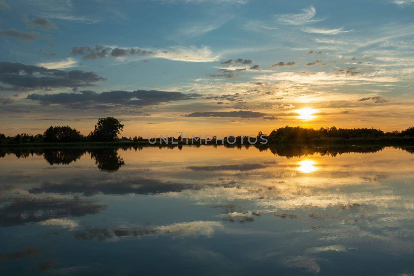 Mirror reflection of clouds in the calm lake water during sunset