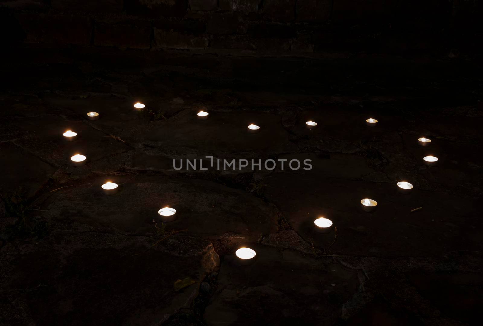 burning tea candles shaped like a heart in the darkness