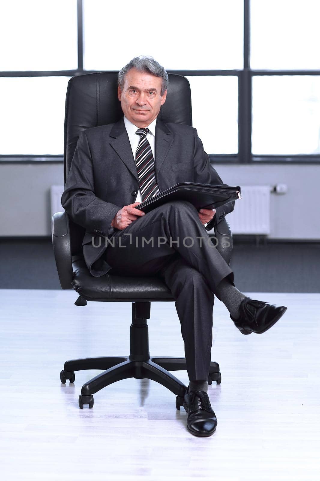 confident businessman with a leather folder, sitting in the office .photo with text space