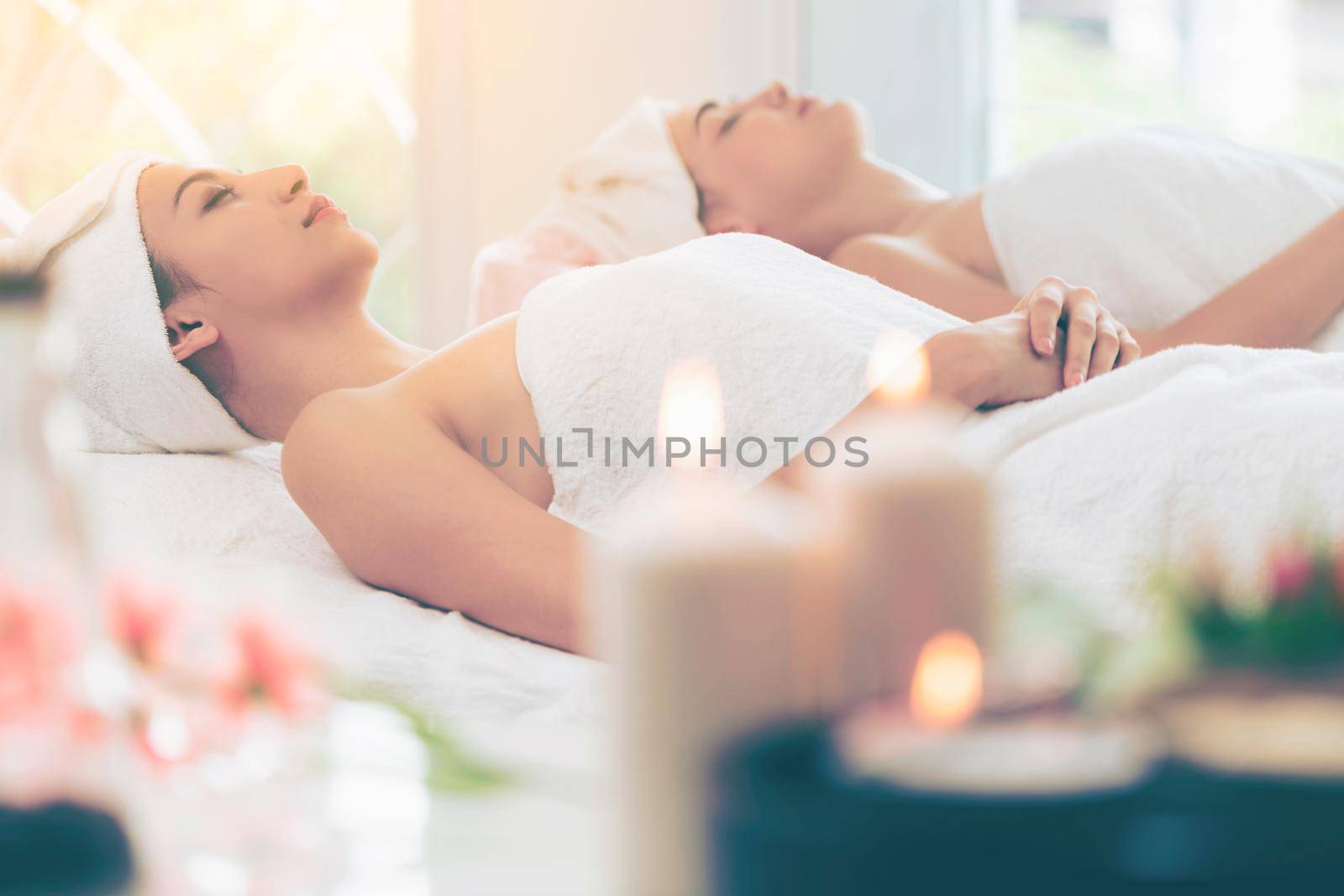 Relaxed young woman lying on spa bed prepared for facial treatment and massage in luxury spa resort. Wellness, stress relief and rejuvenation concept.