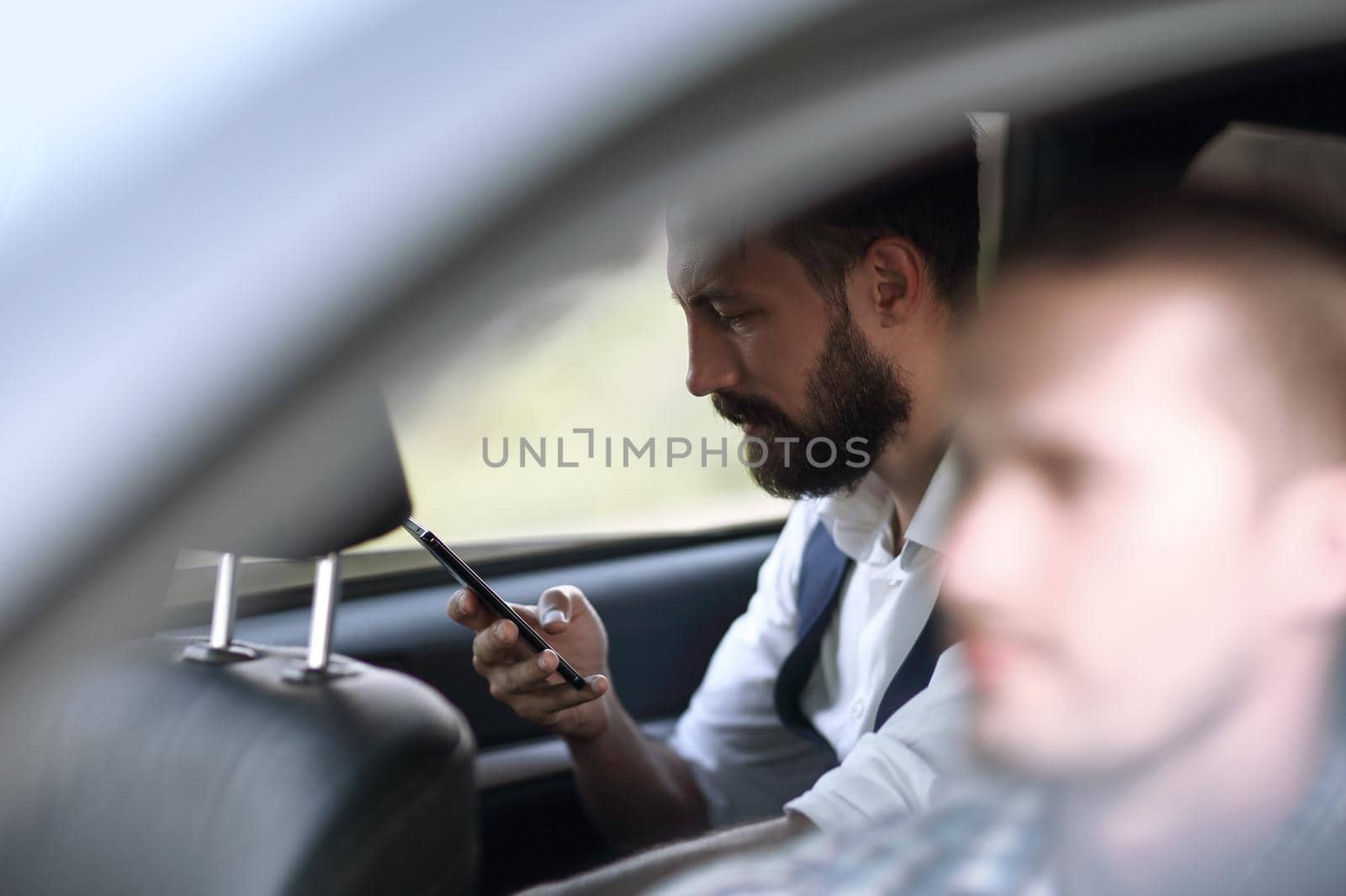 close up.businessman reading SMS on his smartphone, sitting in the car. people and technology