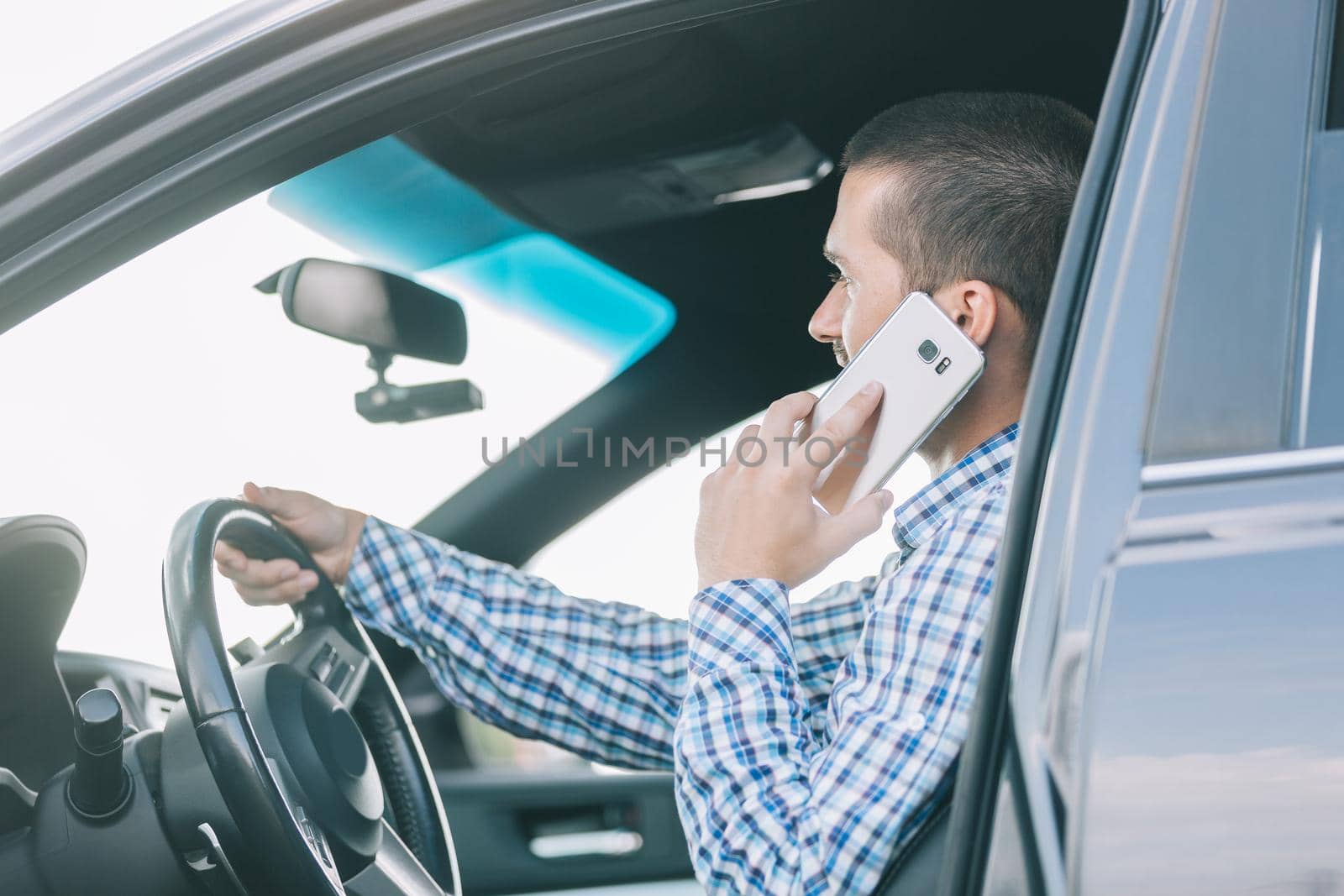 close up.modern man talking on a smartphone, sitting behind the wheel of a car.