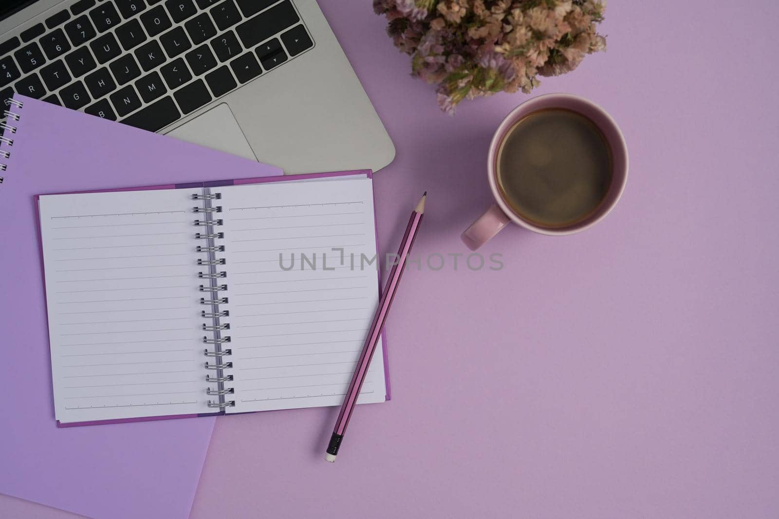 Flat lay laptop computer, notebook and coffee cup on purple background.
