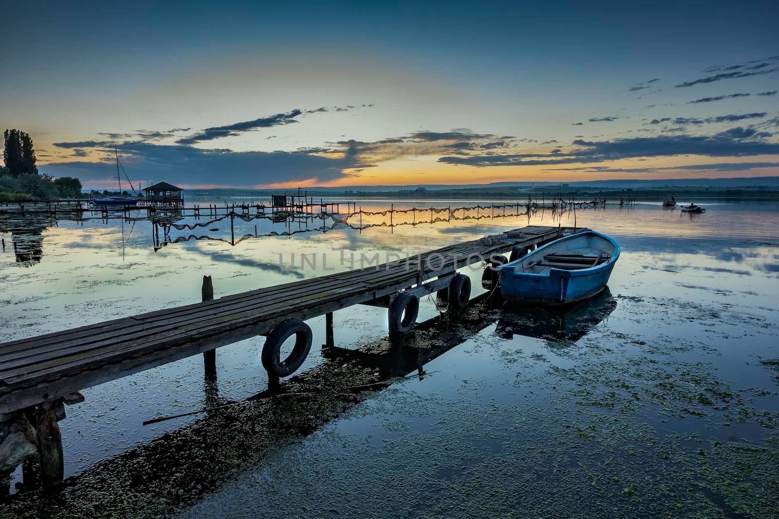 exciting twilight on a shore with pier and boat. Horizontal view