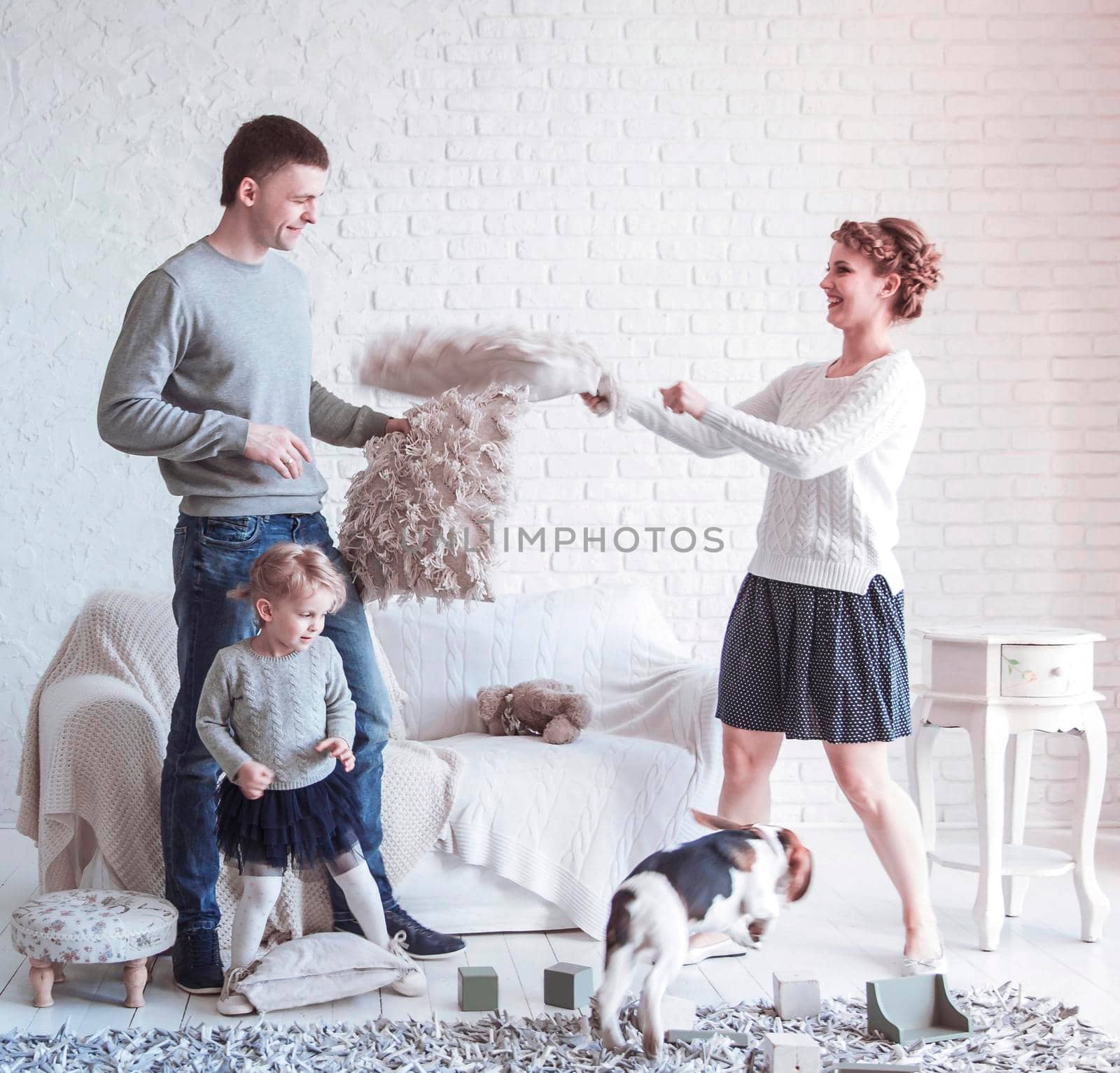 happy parents and five year old daughter playing with a pet dog in the spacious living room on Sunday