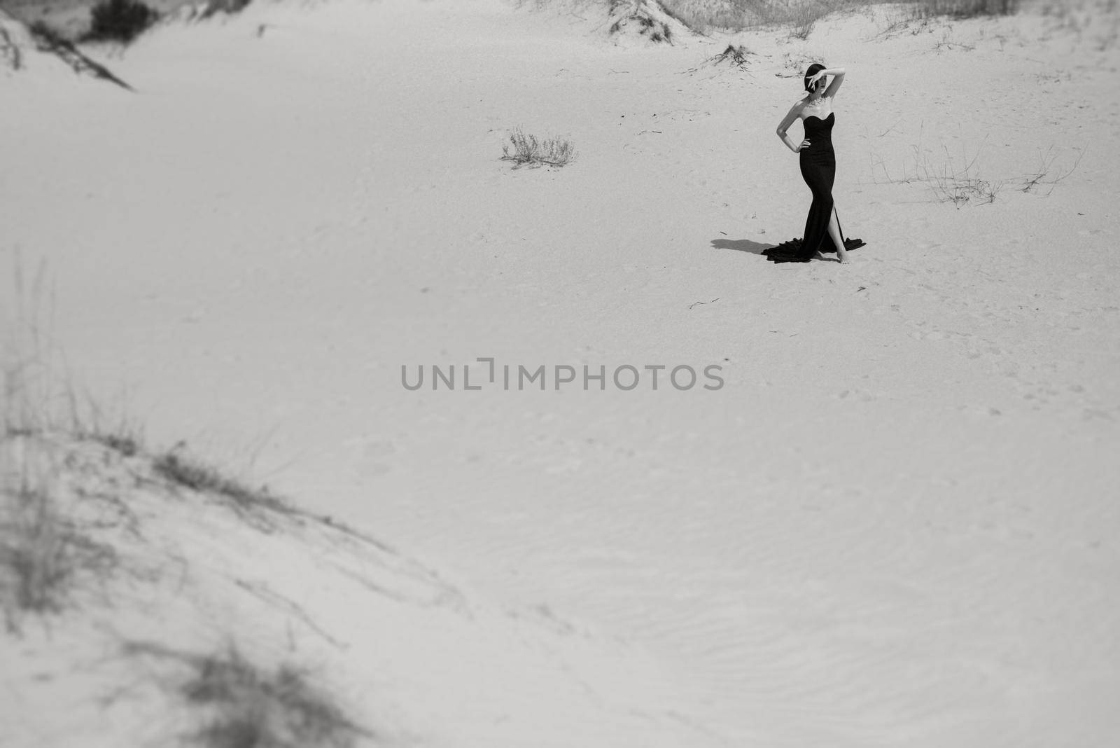 girl in a black long dress in a sandy desert under a blue sky