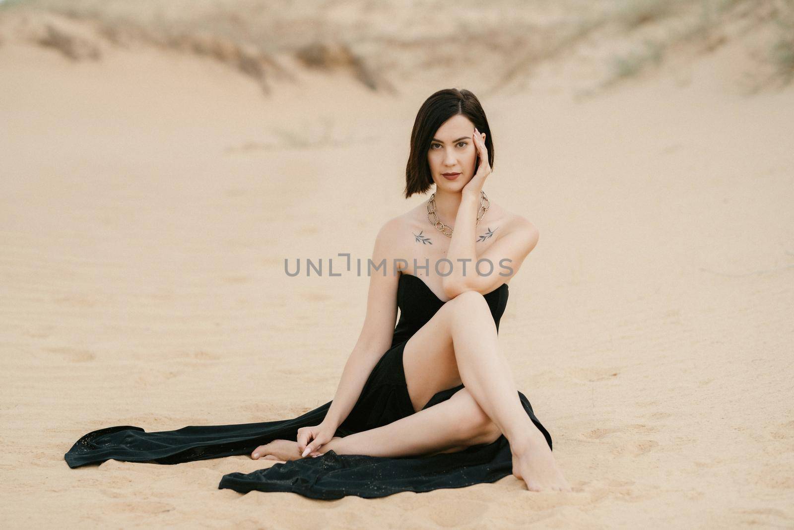 girl in a black long dress in a sandy desert under a blue sky