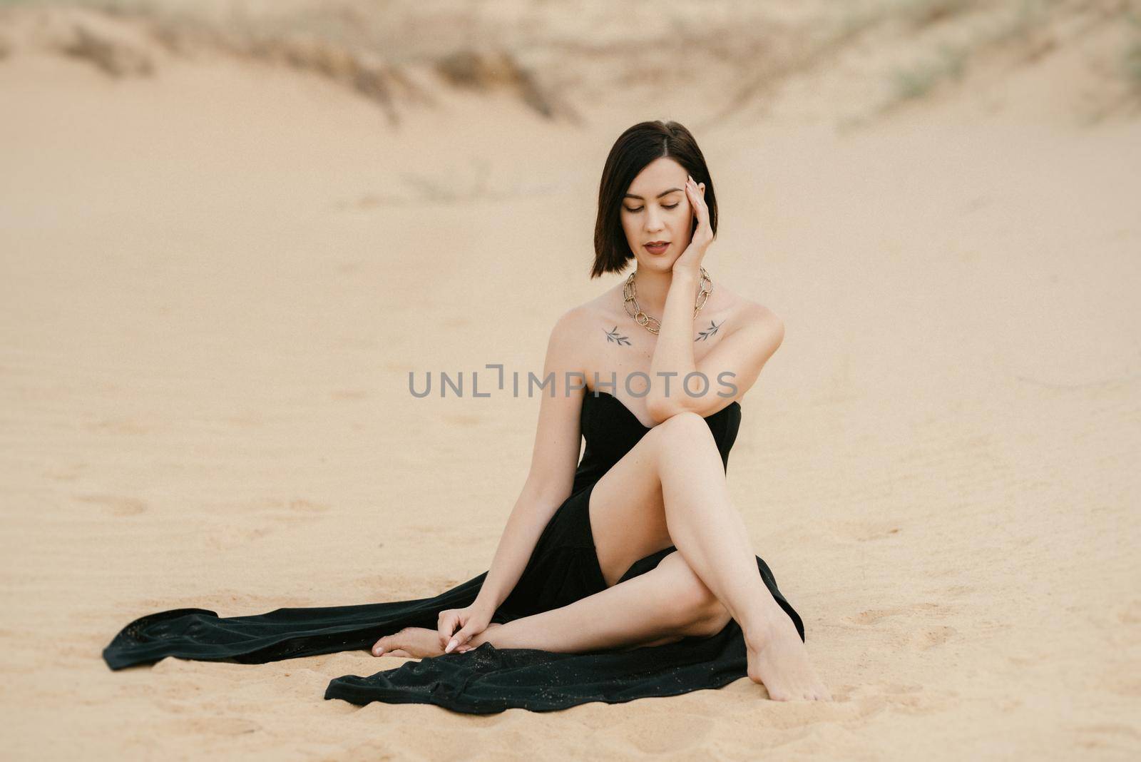 girl in a black long dress in a sandy desert under a blue sky