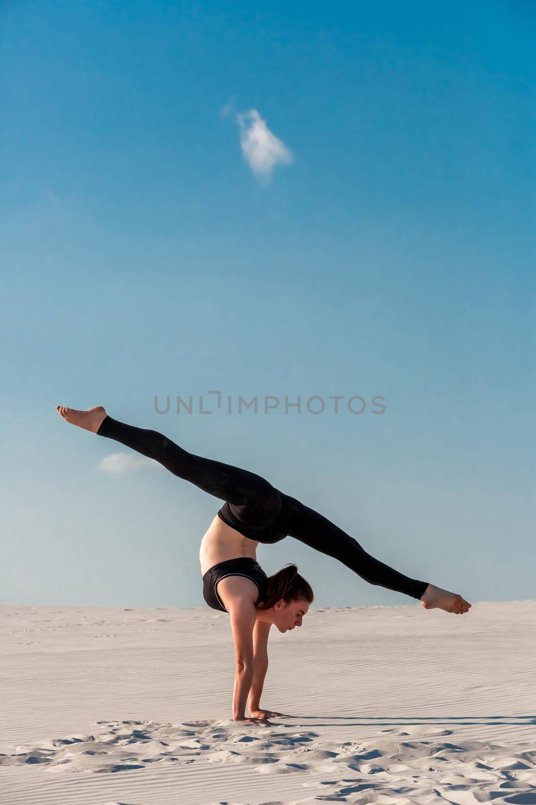 Side view of concentrated fit brunette performing leg and glute workout, doing squats in studio on grey background. Fitness concept