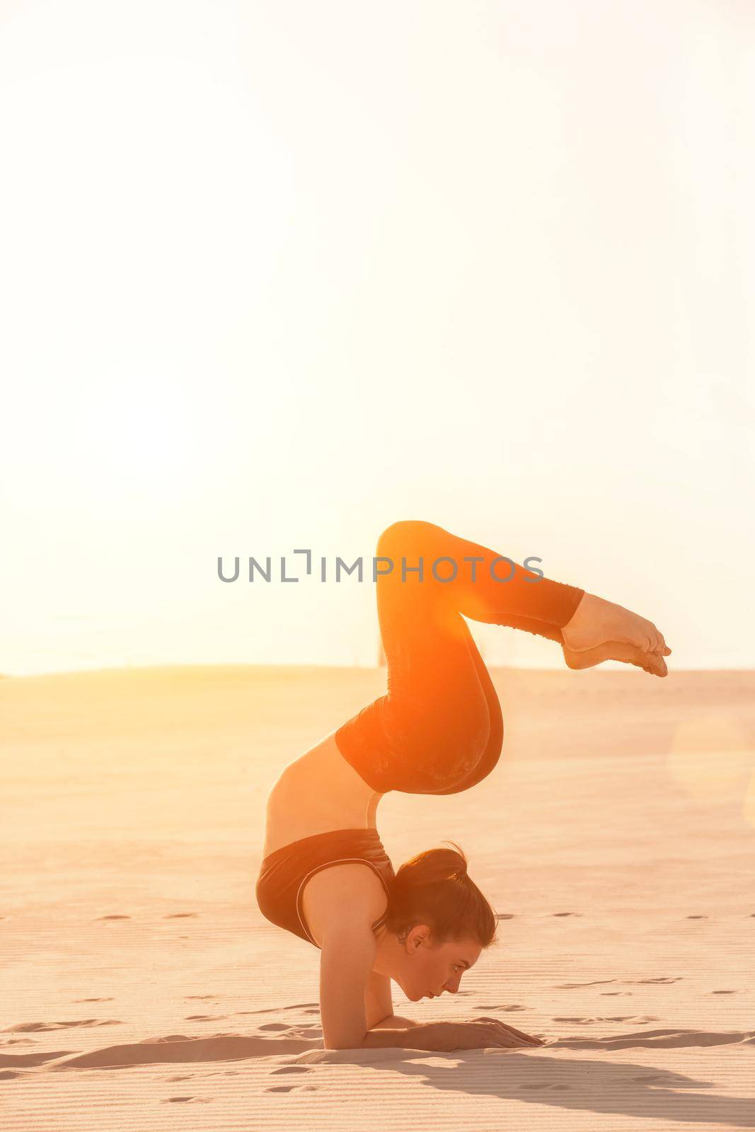 Side view of concentrated fit brunette performing leg and glute workout, doing squats in studio on grey background. Fitness concept