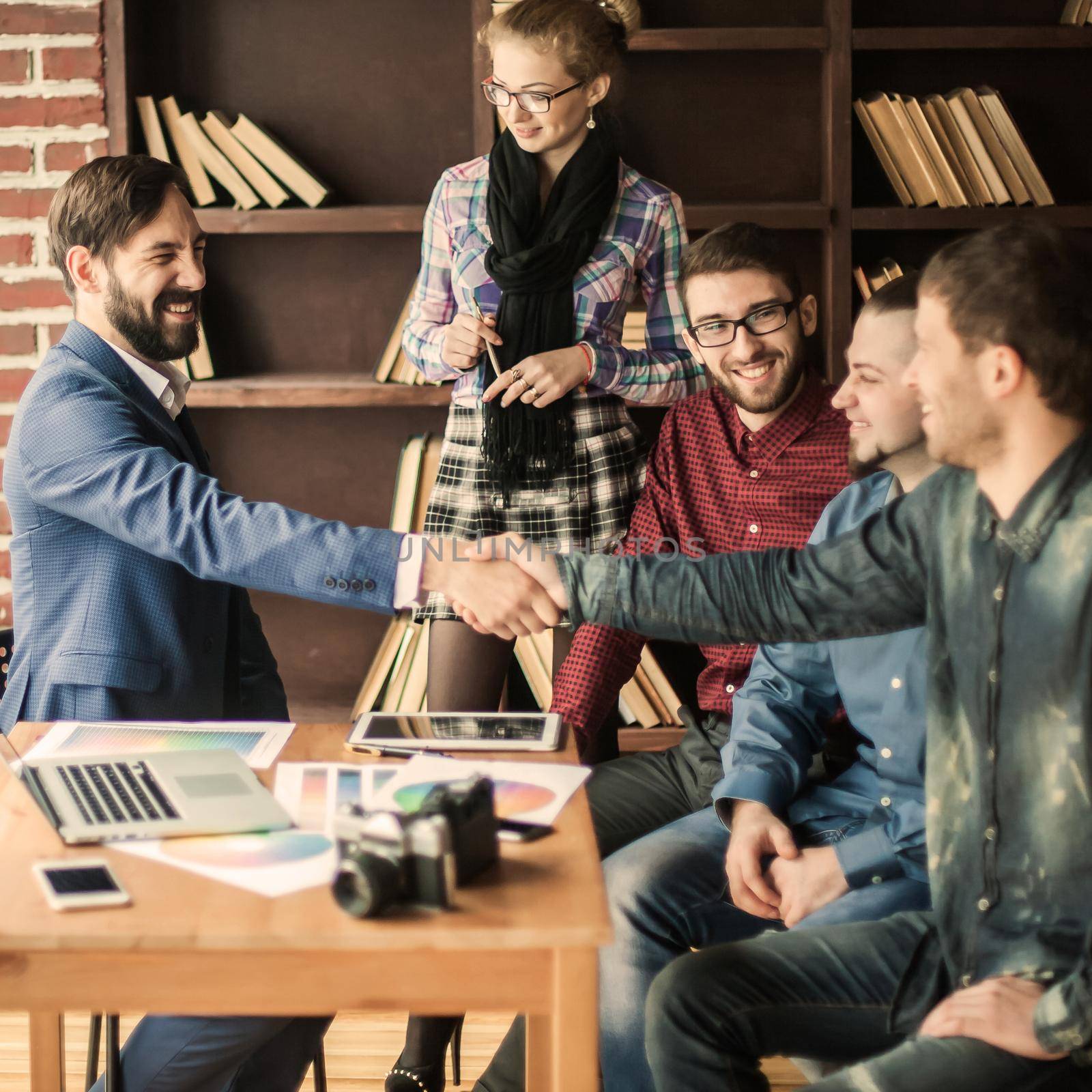 handshake business partners at a meeting in creative office on the background of business team