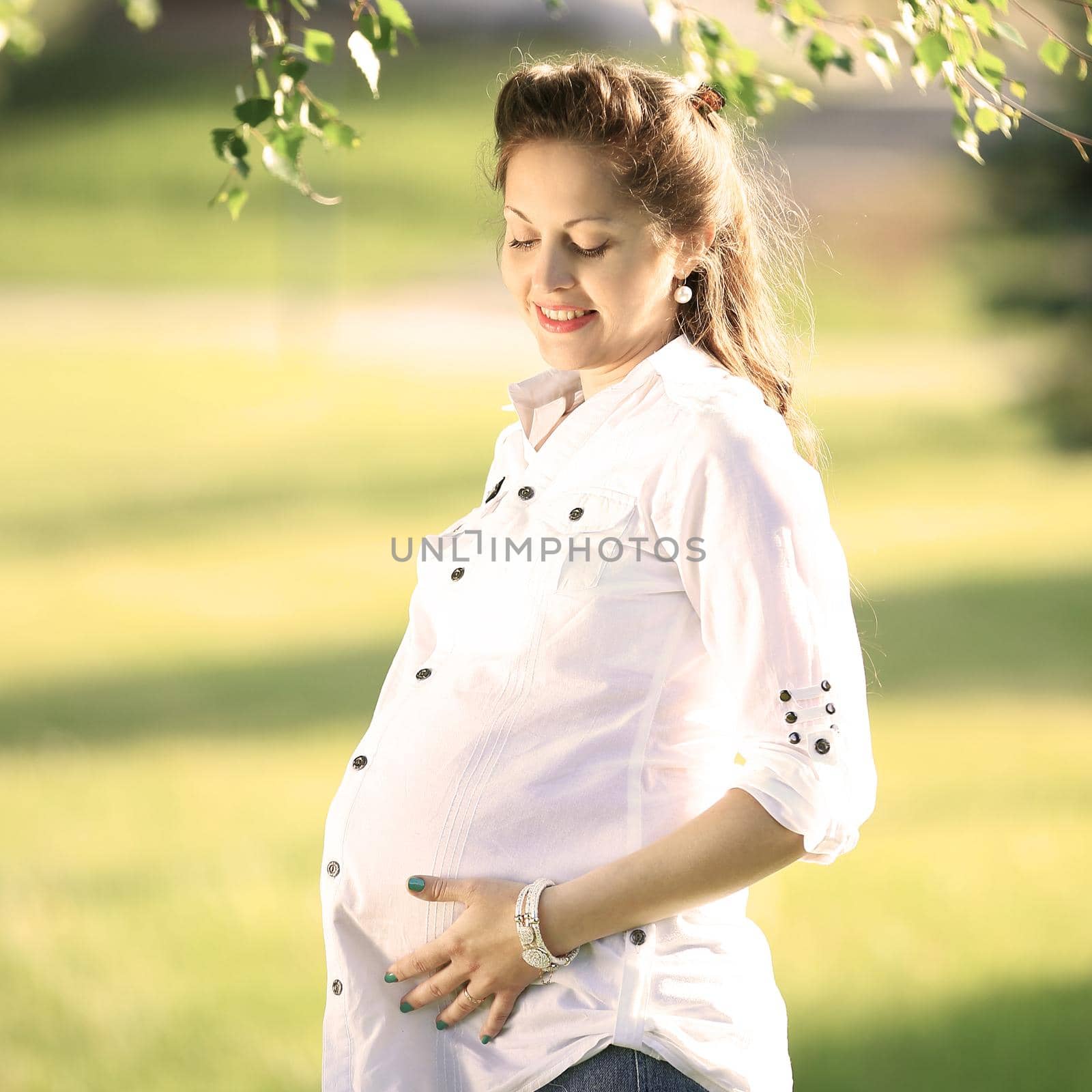 Beautiful pregnant woman relaxing outside in the park by SmartPhotoLab