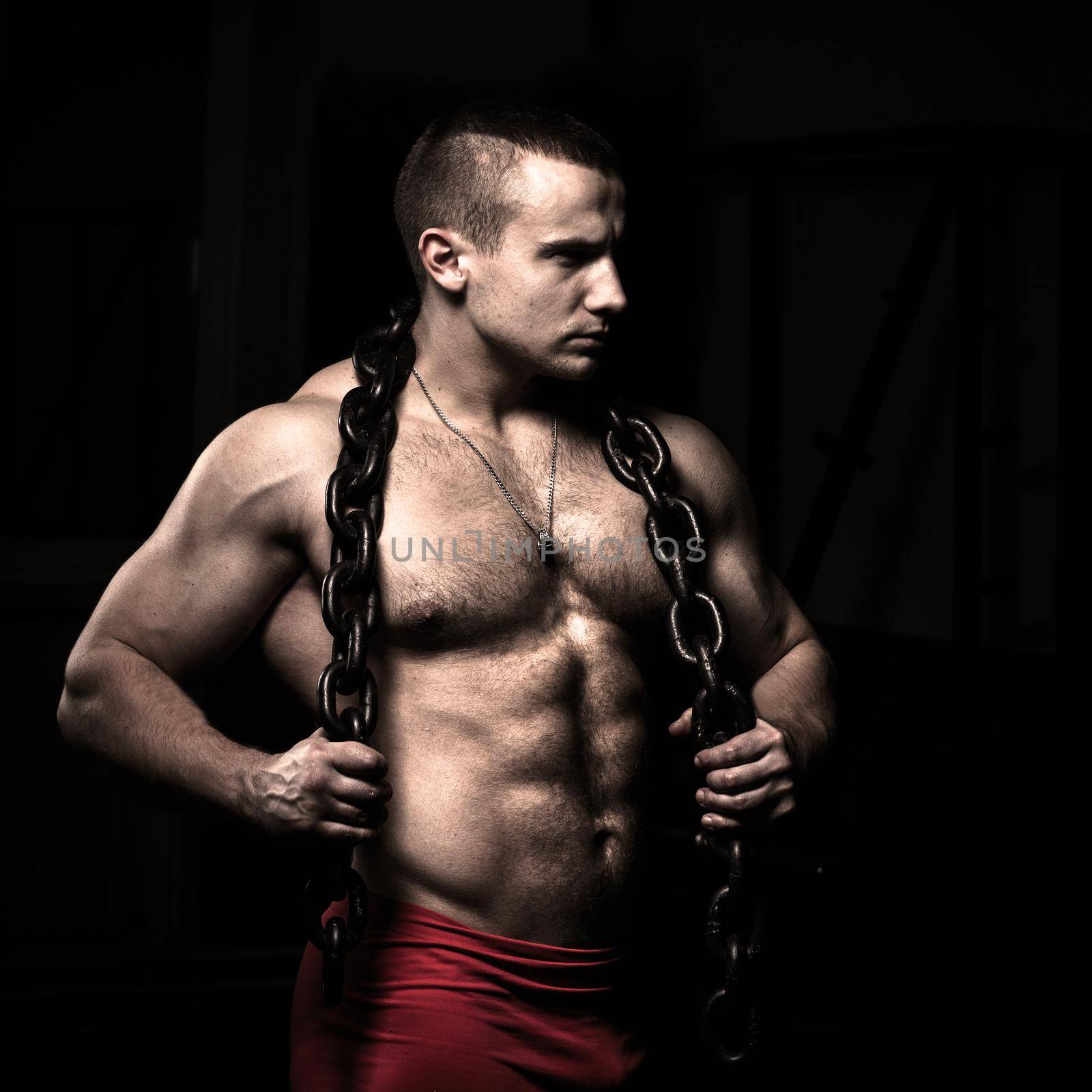 Portrait of a bodybuilder with a chain around his neck on a black background