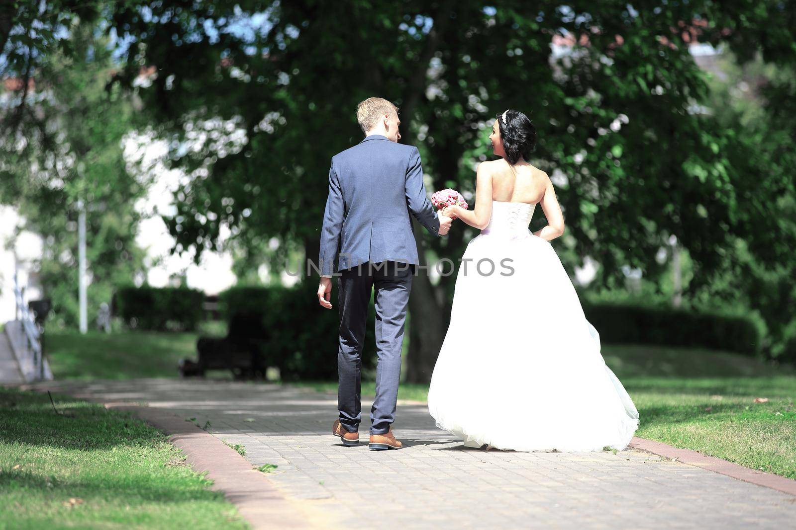 rear view.the happy couple walk through the Park. the day of the wedding.