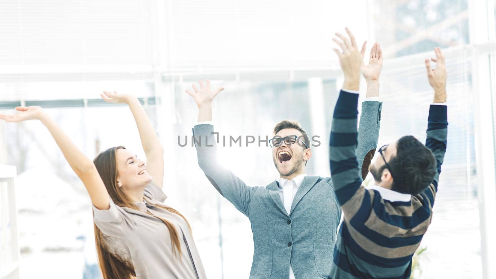 jubilant business team standing in a circle, hands up in rejoice success.the photo has a empty space for your text.