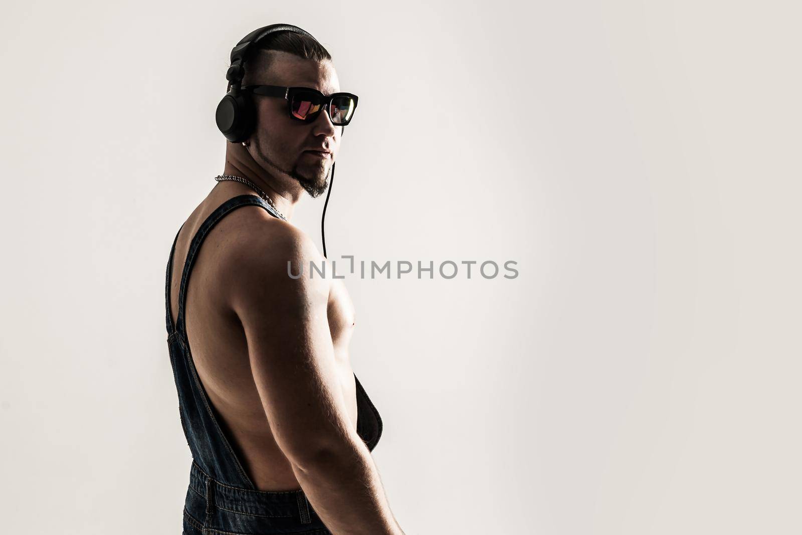 rapper shirtless with headphones and stylish hair on a light background . the photo has a empty space for your text