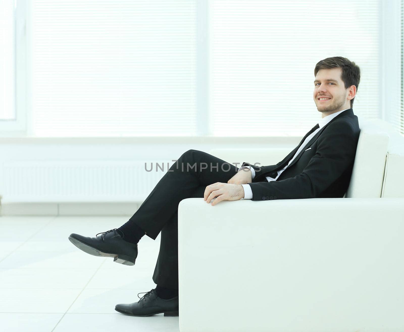 successful businessman sitting in a chair on blurred background office by SmartPhotoLab