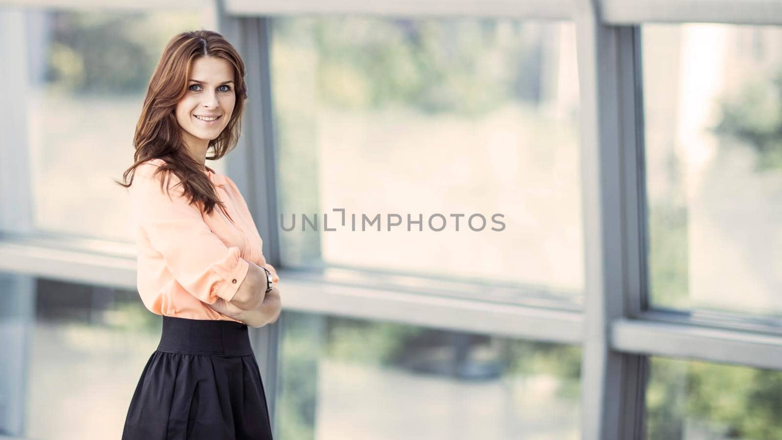 successful business woman near a large window in a modern office. the photo has a empty space for your text