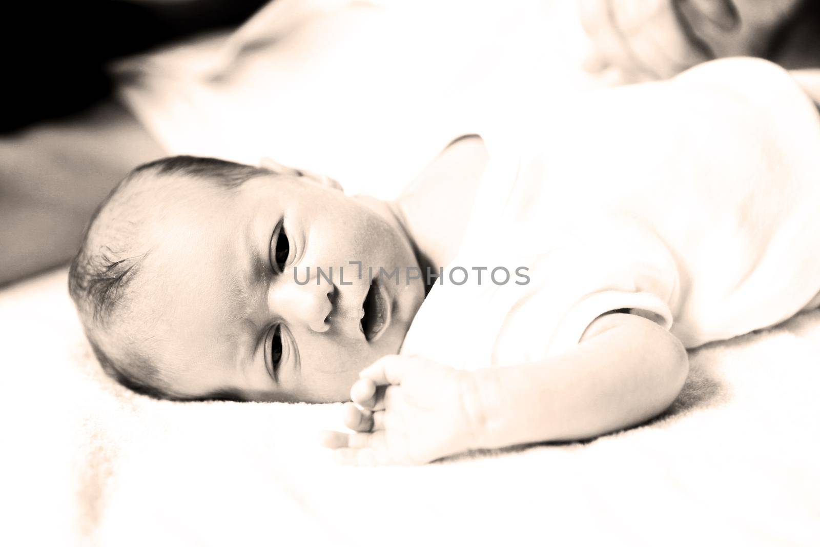 black-and-white photo in retro style: a portrait of newborn baby with mother laying on the bed.