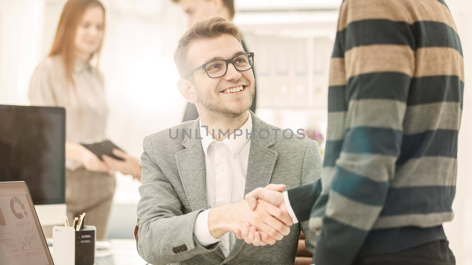 handshake colleagues from the business team near the workplace in the modern office.