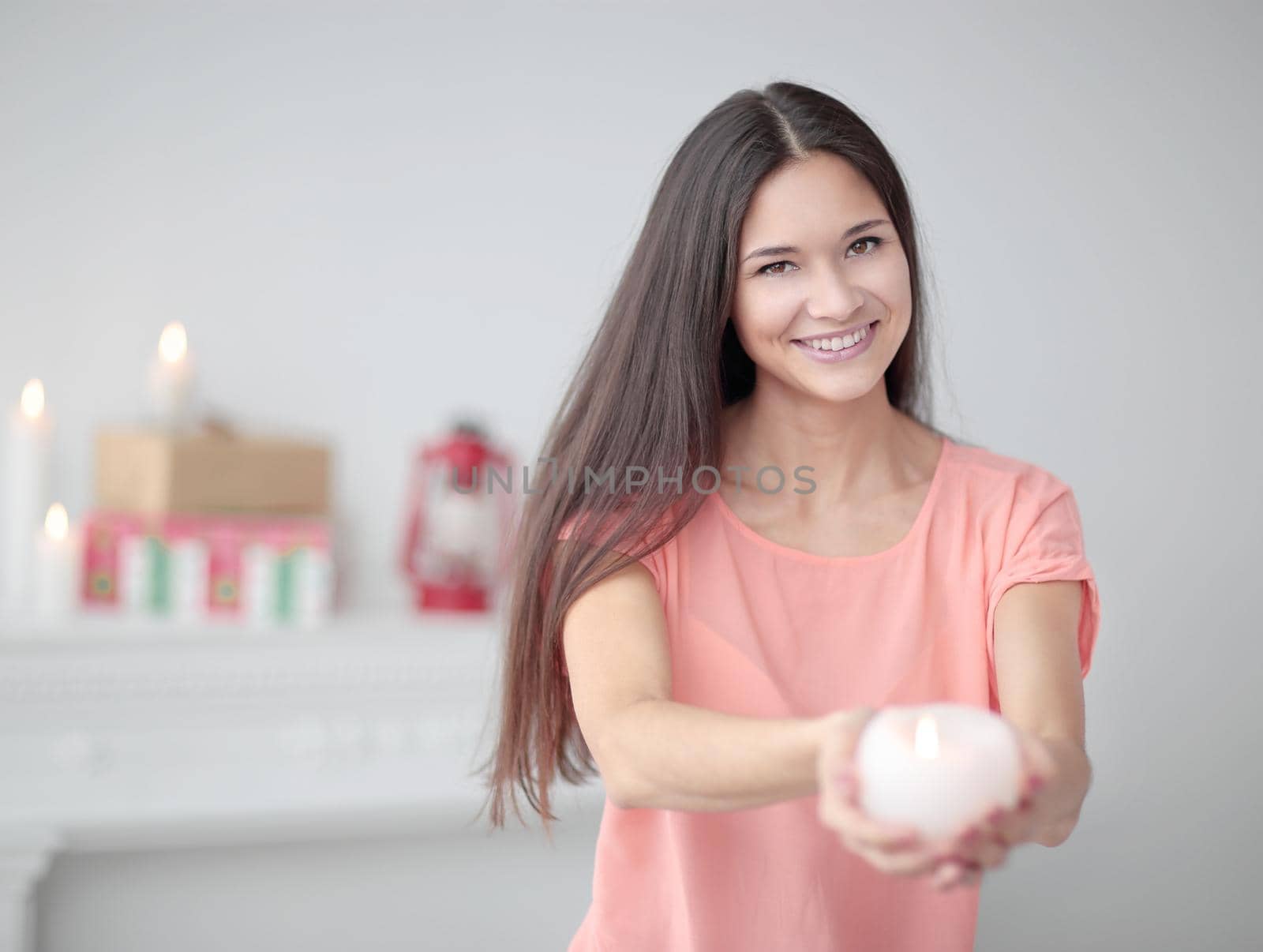 close up.a pretty young woman stretches a burning candle.