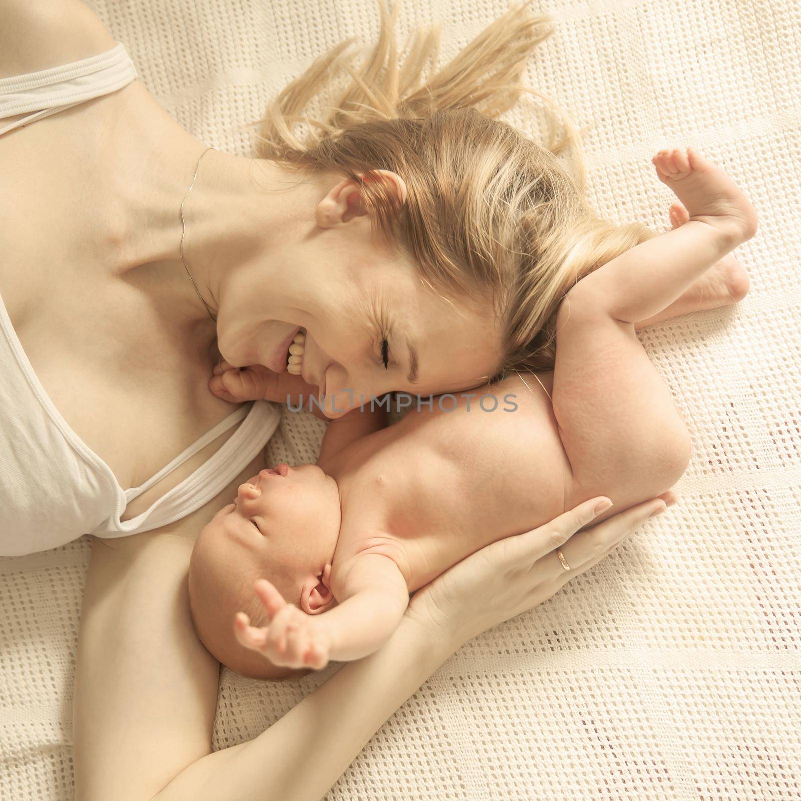 happy motherhood concept - happy mother and newborn baby on a white blanket