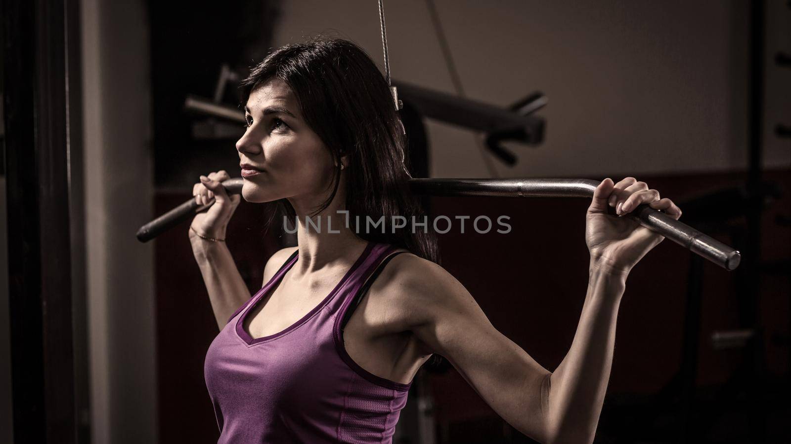 Young business woman doing exercise on a fitness machine in a fitness club. Photo on a dark background.